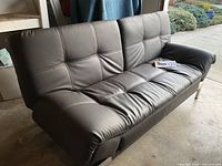 Front view of brown leather futon showing tufted cushions and armrests
