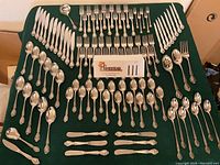 Overhead view of all flatware pieces arranged on green cloth, grouping each type