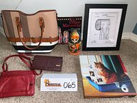 Image shows nesting Matryoshka doll with its book, beige and brown ladies carrying bag, small red handbag, red clutch wallet, framed toilet paper patent art in black frame, and tabby cat reading vinyl art lying on floor.