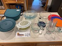 Photo showing full collection of glass and Pyrex kitchenware including bowls, casserole, measuring cups, and lids arranged on a kitchen counter