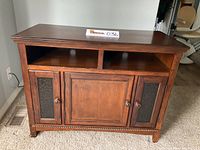 Front view of wooden TV stand cabinet showing two open shelves above three closed storage doors with ventilated side panels and round wooden knobs.