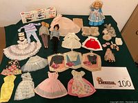 Overview of dolls, clothing and accessories arranged on table