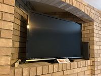 Front view of the Vizio 47-inch TV powered off and resting on a fireplace hearth.
