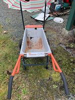 Full view of the wheeled cart showing metal basin with rust and orange metal frame with black grips.