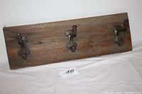 Full view of the wooden board with three cast iron hooks mounted, showing overall condition and mounting holes.