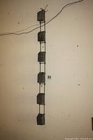 Full view of the entire antique rain diverter hanging against a white wall showing all six rectangular connected metal containers forming the piece, approximately 46 inches long.