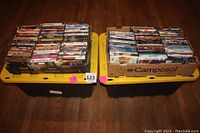 Two large boxes filled with over 120 DVD movies in standard cases, stacked neatly.
