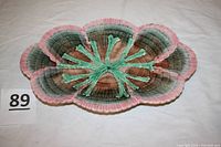 Top view of shell‐shaped platter showing scalloped pink rim, brown-green interior and green raised seaweed design