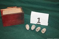 Four Minié musket bullets and small wooden box on green fabric with lot number card
