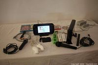 Full lot showing Nintendo Wii U console, GamePad powered on with menu screen, multiple controllers including white and green with straps and covers, black sensor bar, many game discs and cases, HDMI and RCA cords, power adapters, and USB microphones.