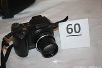 Olympus SP-500UZ digital camera front view with lens extended and camera strap visible