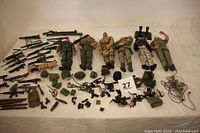 Wide view showing six GI Joe action figures laid out with extensive military accessories including weapons, helmets, packs, and gear, plus plastic tote.