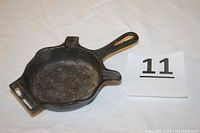 Top view angle showing the cast iron skillet-shaped ashtray with handle and matchbook holder section, marked with lot number 11.