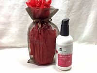BV Spa by Bon Vital moisturizing body lotion in white plastic pump bottle with pink label text next to a brown mesh gift bag with red tissue paper inside.
