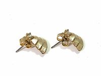 Pair of small gold-tone Christmas tree stud earrings photographed from the side showing textured layers and rhinestone detail.