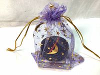 Shiseido blush in a sheer purple organza gift bag decorated with gold stars and moon motifs, closed with gold drawstrings.