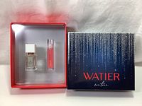 Front view of the open gift box showing two cosmetic items inside, Eau de Parfum and lip oil, along with the Christmas gift box lid with brand and decorative design.