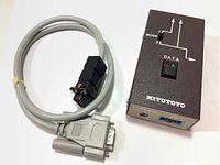 Mitutoyo switchbox next to coiled gray data cable showing connectors.
