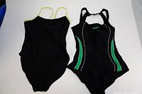Two black one-piece swimsuits on white background, side by side