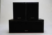 Sony surround sound speaker 3 piece system, two main speakers on top of single center speaker in front, black grille with Sony logo