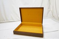 Open view of the vintage wooden box showing mustard yellow cloth interior.