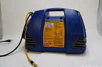 Side view of blue Yellow Jacket refrigerant recovery machine with yellow instruction label and carrying handle.