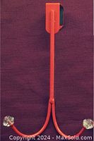 Single close-up photo of a red over the door hanger showing one hook with a clear diamond style knob end and padded door hook section.