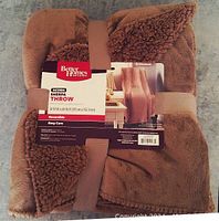 Folded chocolate brown sherpa throw with label showing Better Homes and Gardens brand, size 50x60 inches, reversible, easy care and machine washable.