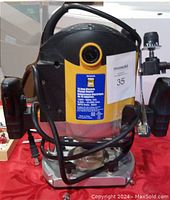 Front view of Power Fist electric plunge router showing label, handles, and mounting brackets on red cloth.