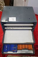 Top view of metal stacking drawer with open drawers showing cardboard lining and blue and orange plastic compartment inserts.