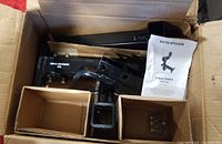 Black metal engine lift components including a main arm, mounting hardware, and an instruction sheet in a box.