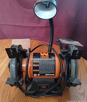 Front view of the WEN 6 inch bench grinder showing both grinding wheels, protective shields, and flexible lamp attached.