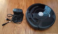 iRobot Roomba robot vacuum and charging base on wooden floor.
