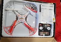 Striker Spy Drone quadcopter inside white packaging tray with its remote control and manuals/warranty papers in box