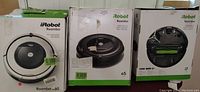 Three boxed Roomba robotic vacuums from left to right: Roomba 60, Roomba e5, and Roomba i7.