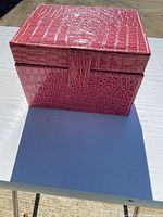 Front view of the pink faux crocodile textured jewelry box showing rectangular shape and clasp.