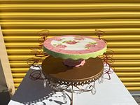 Zrike ceramic cake platter with painted roses on a pink and green scalloped base, shown stacked on gold metal platter and red cupcake holders