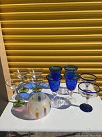 Photo showing all items: 4 cobalt blue stemmed glasses, 4 clear martini glasses with green stems, 2 cobalt blue rimmed daiquiri glasses, and round frosted hand-painted vase