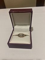 Ring displayed inside hinged jewelry box, front view.