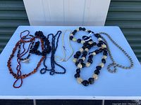 Full view of all six necklaces arranged on a white surface showing size and style differences.