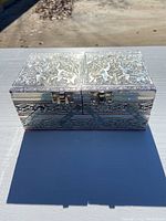 Front view of the silver jewelry box showing the clasp and embossed elephant design on the top halves.