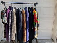 Full rack of ladies business casual clothing including various blazers, jackets, and patterned tops in sizes 10 and 12.