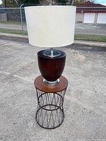 Barrel-shaped lamp with white drum shade placed on the end table, showing overall appearance and condition.