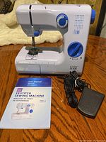 Overall view of the Easy Home 19 Stitch Sewing Machine with included user manual and foot pedal cord.