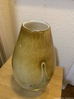 Front perspective of the large green glass vase showing its shape and color gradation, placed on a wooden surface with a plain wall background.