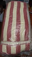 Full view of folded cotton towel showing red and cream stripe pattern wrapped in plastic.