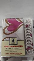 Photos of the new packaged water repellent fabric shower curtain with pink and brown design and 12 fabric covered rings, 100% polyester.