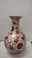 Front view of the porcelain Chinese vase showing the red floral and gold vine pattern on a white base.