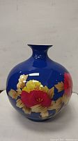 Full frontal view of the blue vase showing its rounded body and floral design.
