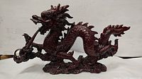 Front and side views of the dark reddish-brown dragon sculpture with detailed scales and facial features, holding a clear orb.